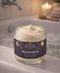 Jar of Whole Rituals whipped tallow magnesium on a bathroom counter with a candle in the background.