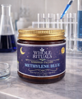 Jar of Whole Rituals Methylene Blue on a laboratory counter with test tubes in the background.
