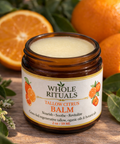 Jar of Whole Rituals Tallow Citrus Balm with oranges and leaves in the background