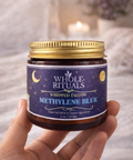 Jar of Whole Rituals Methylene Blue cream held by a hand with a soft blurred background