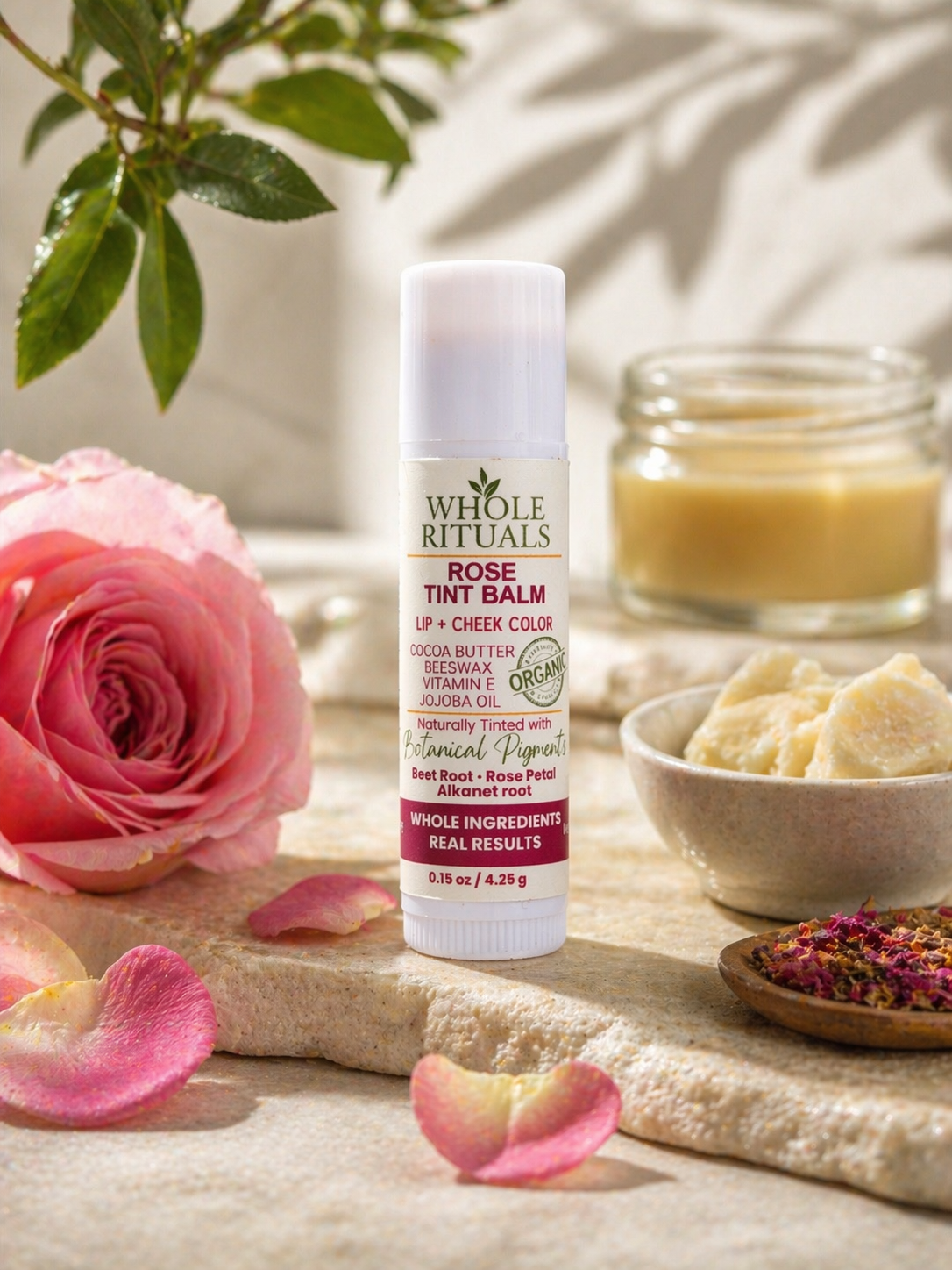 Whole Rituals lip balm with a pink rose and rose petals on a natural background