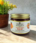 Jar of Whole Rituals Tallow Citrus Balm on a wooden surface with a plant in the background