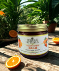 Jar of Whole Rituals Tallow Citrus Balm on a wooden surface with oranges and plants in the background